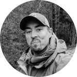 Profilbild von Der Bommel – 7 vs. Wild Teilnehmer und Bushcraft-Spezialist, präsentiert sein vielseitiges Nalgene Challenge Setup mit Angelset, Leatherman und Feuerstahl.