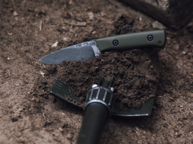FOSSOR MK1 Damastmesser FOSSOR MK1 aus Wildem Damast neben einem Bundeswehr-Dreifachspaten.